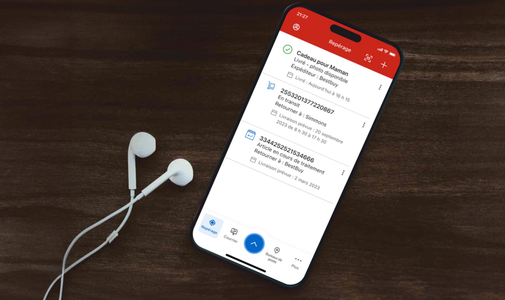 Un cellulaire est utilisé pour suivre des envois dans l’appli de Postes Canada. Des écouteurs sont posés à côté du cellulaire