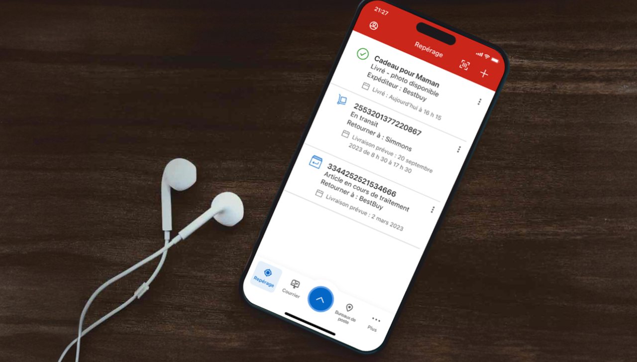 Un cellulaire est utilisé pour suivre des envois dans l’appli de Postes Canada. Des écouteurs sont posés à côté du cellulaire