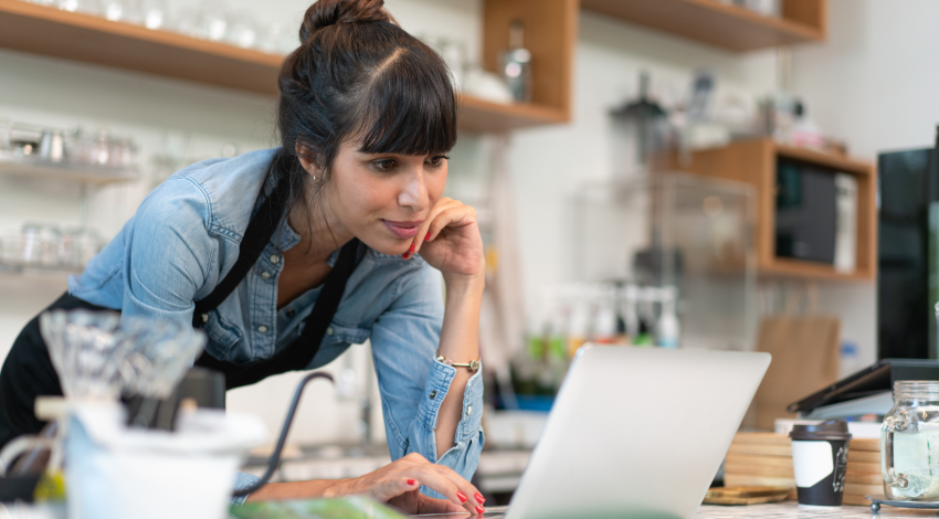 Au comptoir d’un café, une employée est penchée sur son ordi portable.