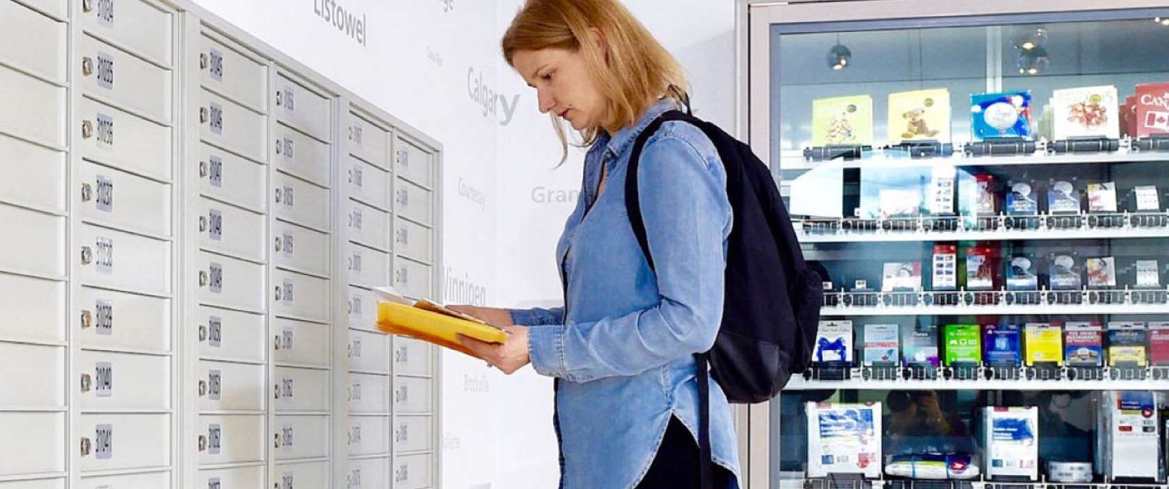 Une femme dans un bureau de poste examine une petite pile de courrier récupérée dans sa case postale de Postes Canada